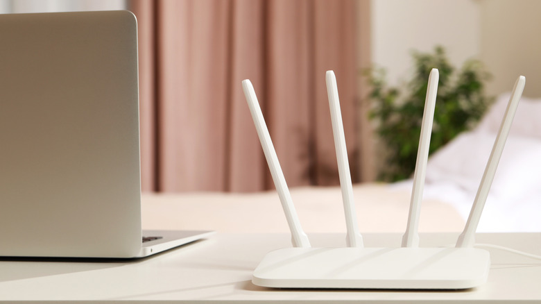 A laptop next to a Wi-Fi router on a table