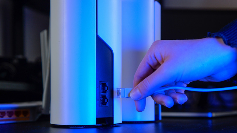 A close up of someone plugging an ethernet cable into a mesh wi-fi unit