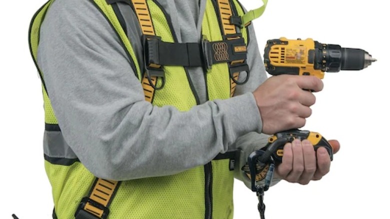 Person holding a drill with a lanyard attached