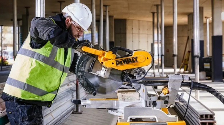 Worker cutting board with DeWalt 15 Amp 12-inch Double Bevel Sliding Compound Miter Saw