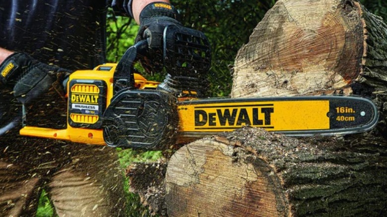 Person cutting log with DeWalt 60V Max 16-inch Brushless Chainsaw