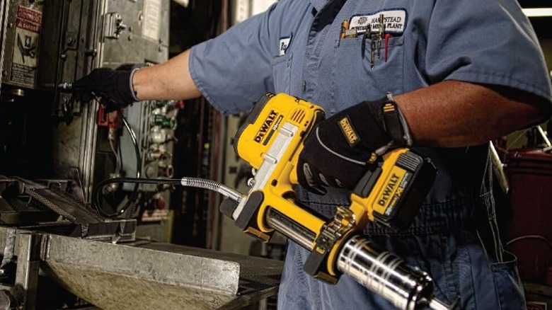 A person holding a DeWalt grease gun.