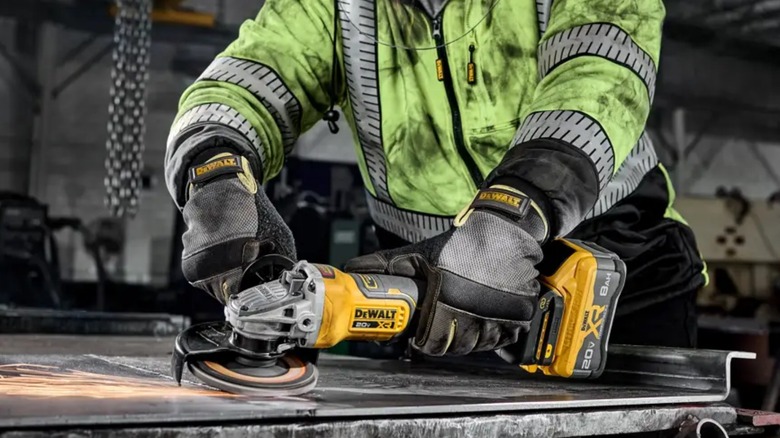A person using a DeWalt grinder on metal.