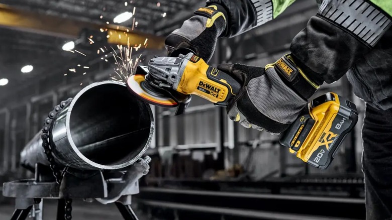 A person using a DeWalt grinder on metal.
