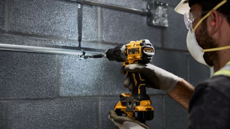 A person using a dewalt 20-volt hammer drill with built-in belt clip