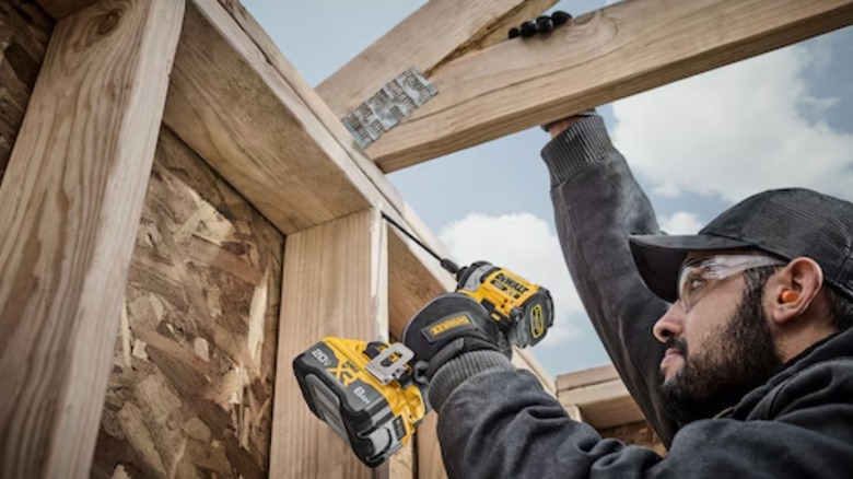A person using a DeWalt 20-volt impact driver with built-in belt clip