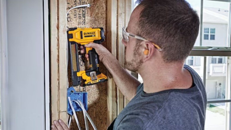 A person using a DeWalt 20-volt stapler with built-in belt clip