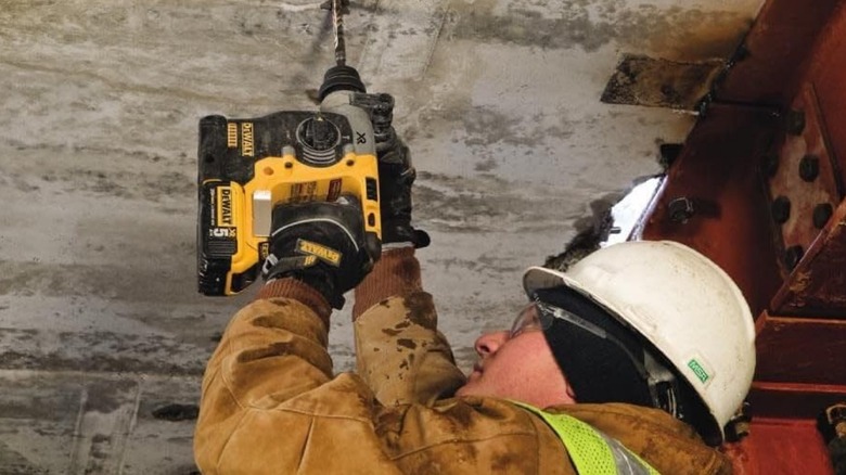 A person using a 20-volt DeWalt rotary hammer with built-in belt clip (utility hook)
