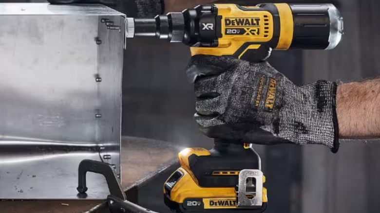 A person using a DeWalt 20-volt rivet tool with built-in belt clip