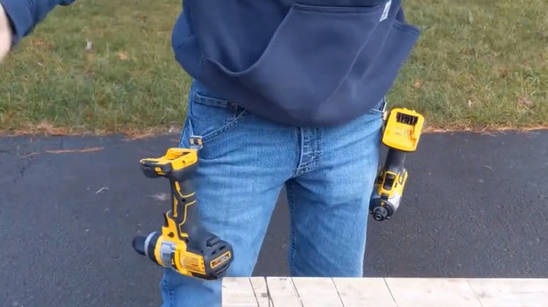 A person with DeWalt power tools hanging from their pockets using the built-in belt clips