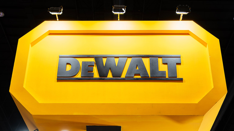 The DeWalt logo on a yellow billboard with lights shining above it.
