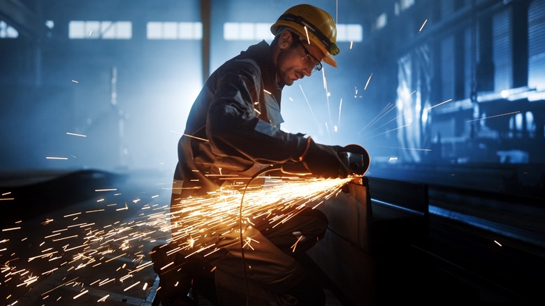 Worker using power grinder