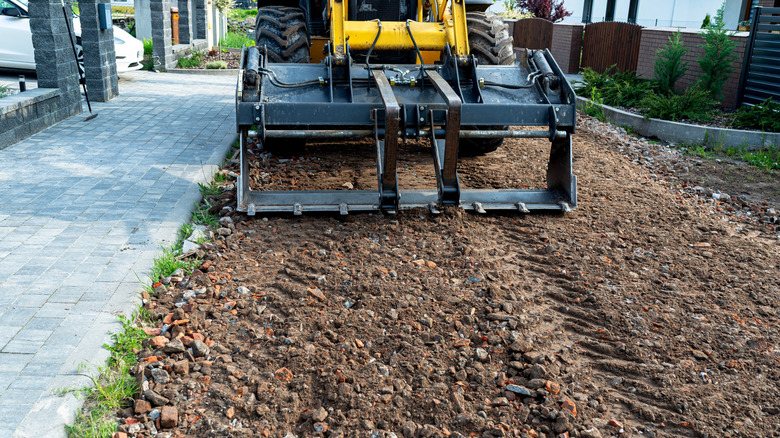A backhoe loader leveling a rocking path.