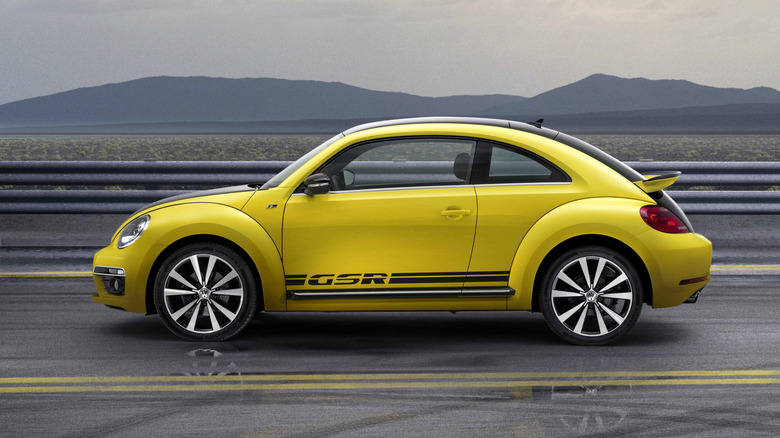 Yellow and black 2015 Volkswagen GSR seen from directly left with guardrails and mountains behind it