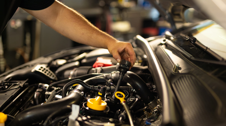 Mechanic checking car's oil level in garage