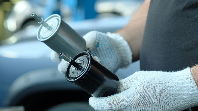 Mechanic holding two fuel filters