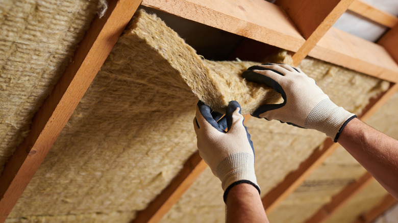 Close up of person removing wall insulation