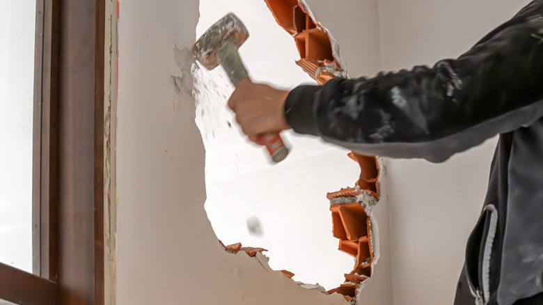Person knocking down wall with sledge hammer