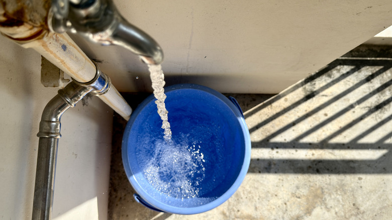 Overhead view of a blue bucket collecting water from a tap