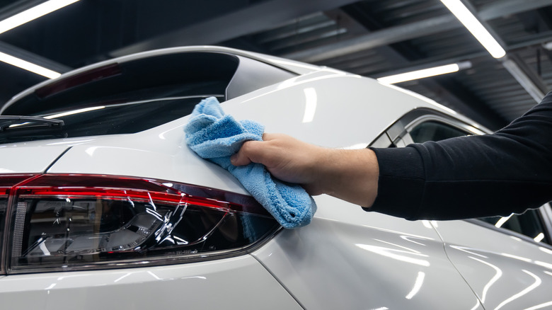 person wiping car with cloth towel