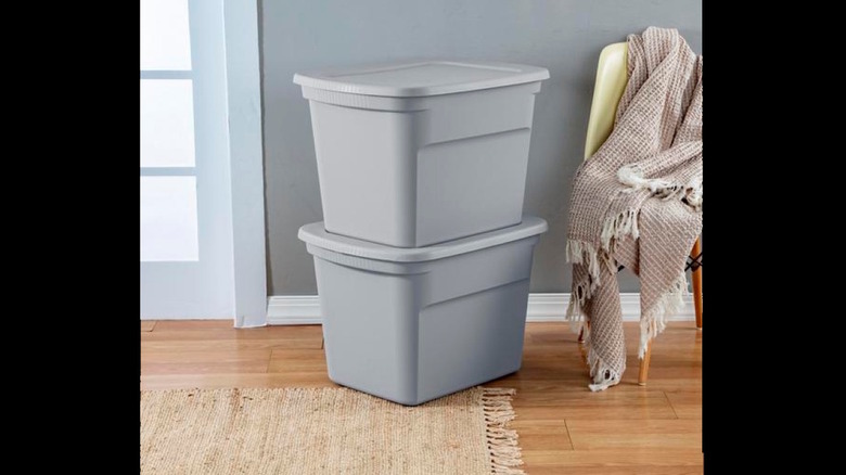 two storage totes stacked next to a chair
