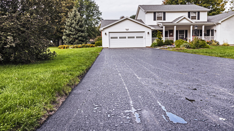 Water beading on an asphalt driveway in front of a house.