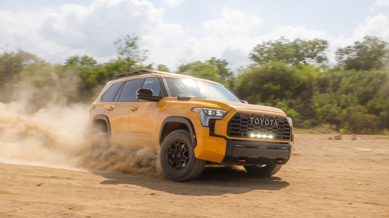 Front 3/4 view of yellow Toyota Sequoia sliding through dirt.