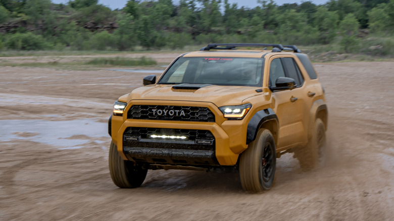 Front view of yellow Toyota 4Runner driving in mud pit.