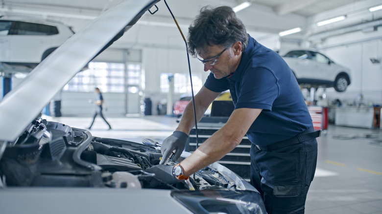 Mechanic servicing a car in a white professional garage
