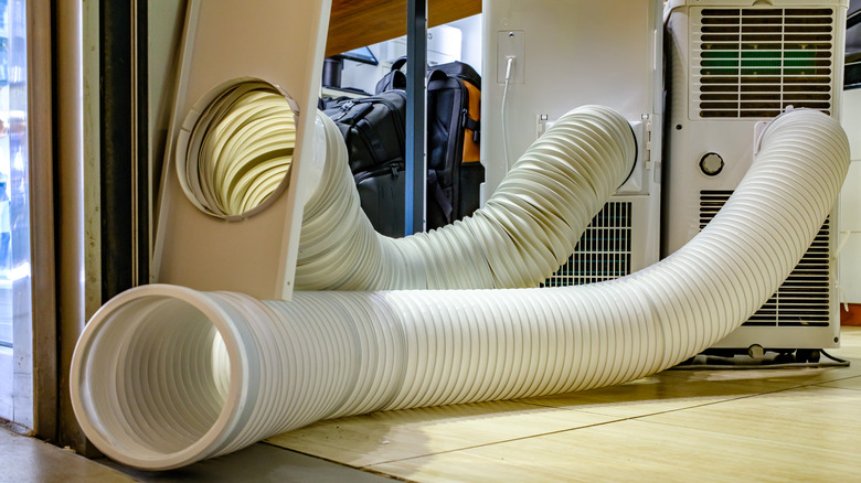 Portable air conditioner with vent hoses running untidily along the floor