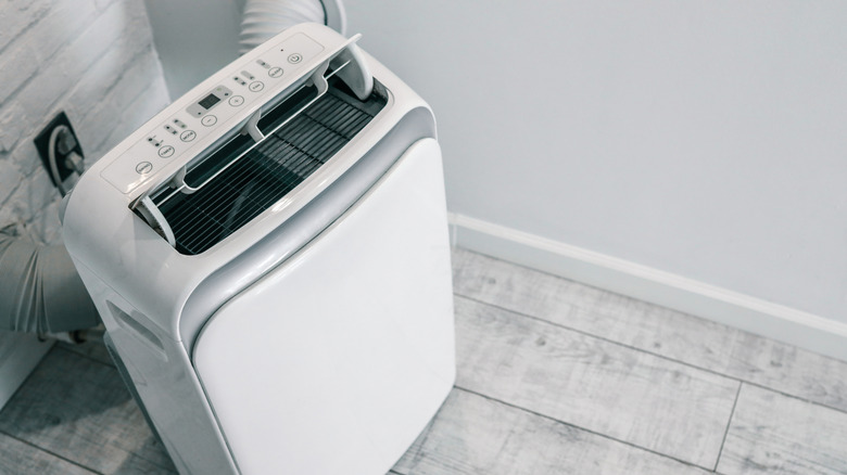 Portable air conditioner with two vent hoses feeding through walls