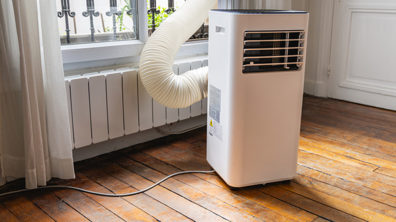 Portable air conditioner sitting near a window with vent hose showing