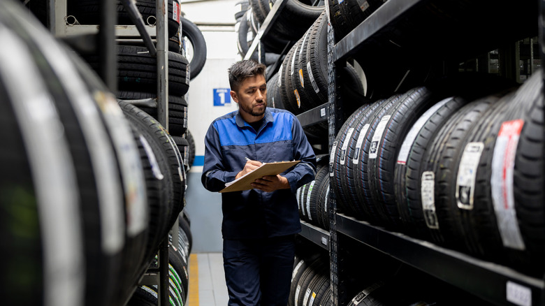 A person holding a form walking through tire shelves.