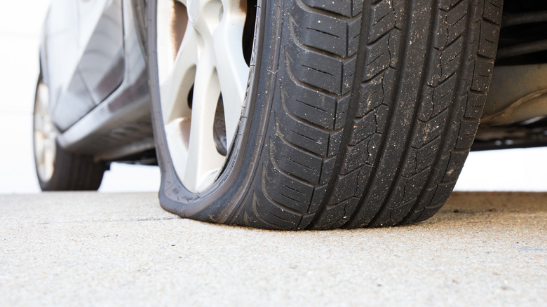 A close-up of a flat tire on a car.