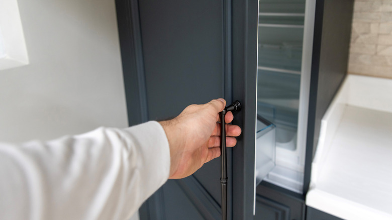 A person opening the door on a built-in fridge.
