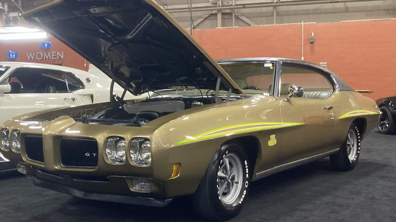 1970 Pontiac GTO parked indoors at car show with hood open, front-left 3/4 view