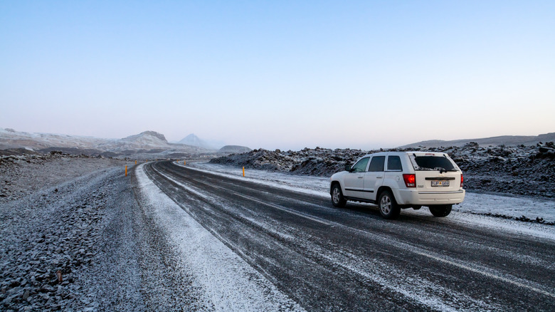 A white Jeep Grand Cherokee driving on snow-covered roads in a remote snowy location.