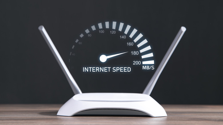 A wi-fi router with two antennas placed on a wooden table with a speedometer graphics above it depicting internet speed