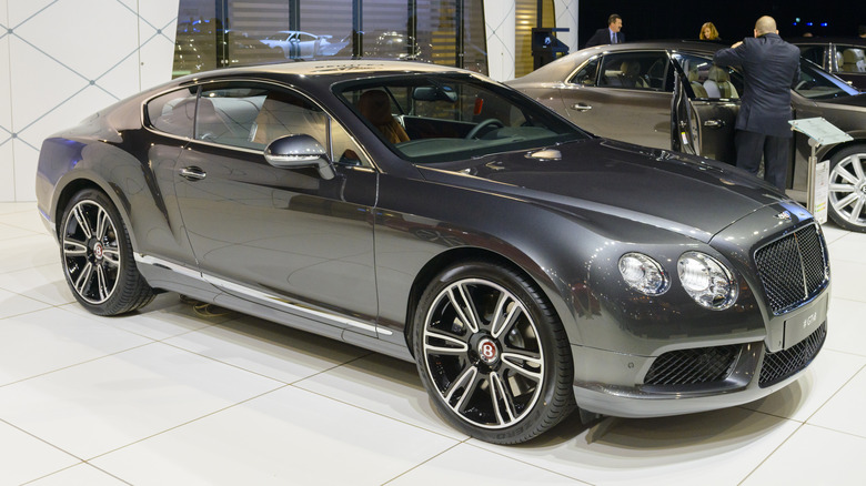 A gray Bentley Continental GT coupe on display at the 2014 Brussels motor show, indoors.