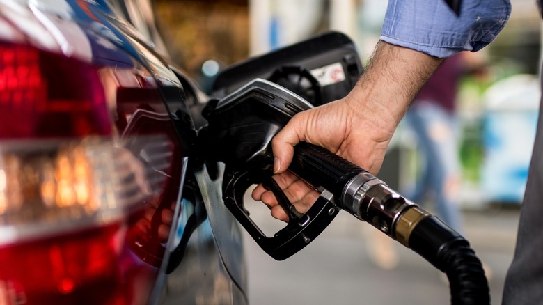 Hand holding nozzle to gas tank