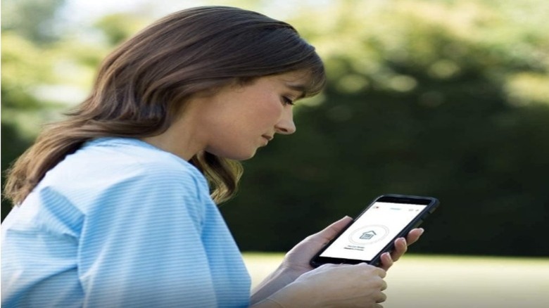 Woman holding smartphone displaying a "home" icon