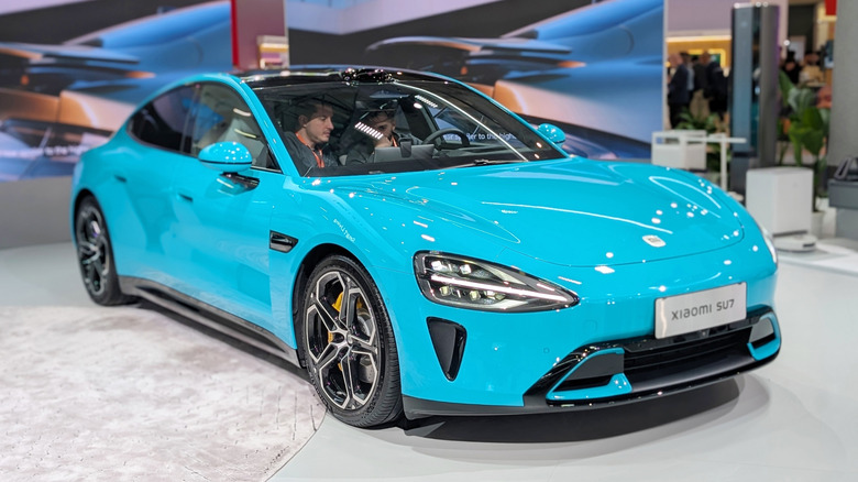 A baby blue Xiaomi SU7 sedan on display at an event in Barcelona