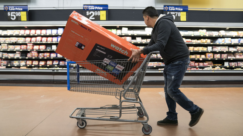 Person carrying a TV in a Walmart shopping cart