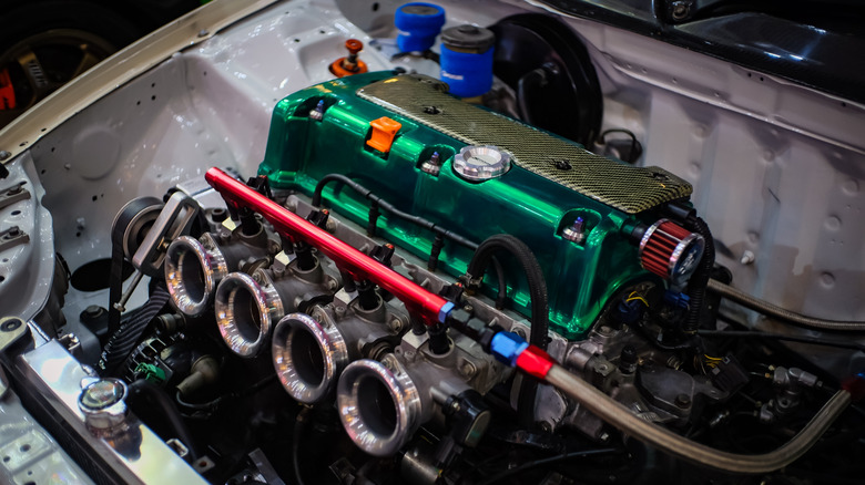 A fully built Honda K20 four-cylinder with individual throttle bodies and a custom green cam cover