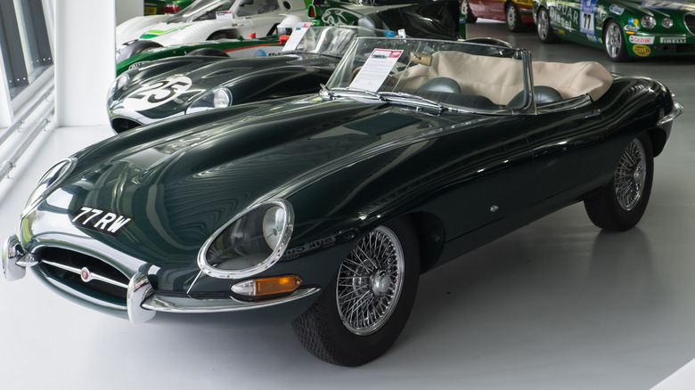 Green 1961 Jaguar E-Type roadster seen from left front parked in a showroom