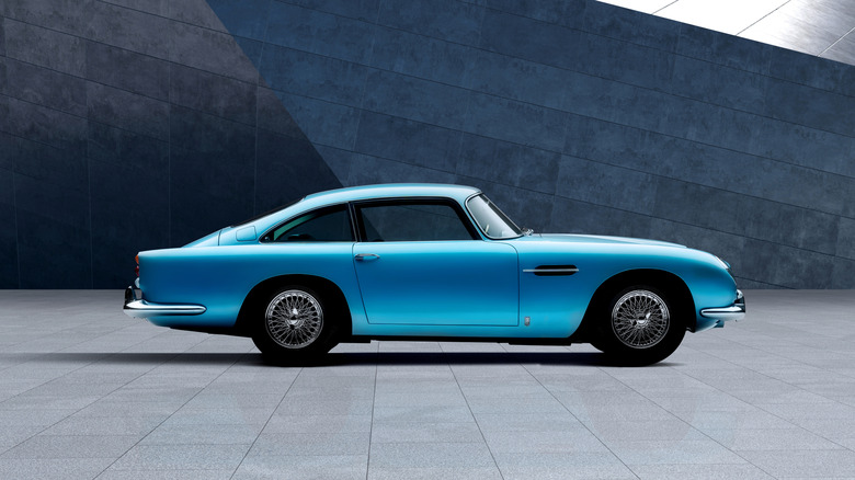 Blue Aston Martin DB5 sports car seen from the right against a modern architecture background