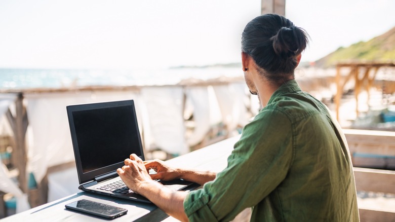 Person on laptop staring at the beach