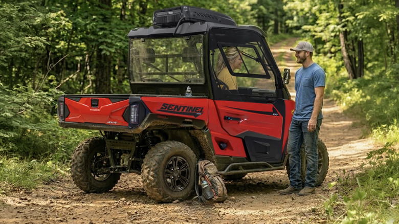 People talking next to a Massimo UTV on a dirt road