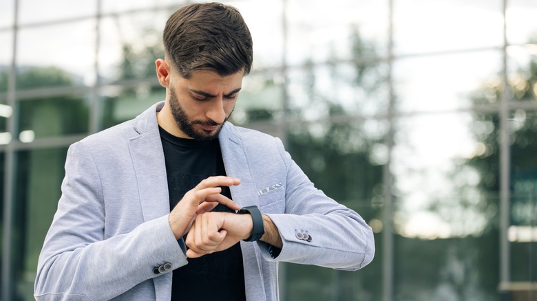 man wearing suit using smartwatch