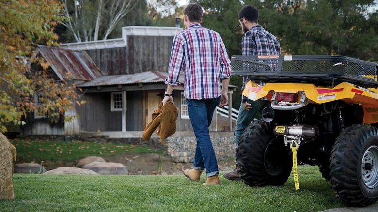 Two men moving away from a four-wheeler ride in a garden.